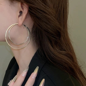 Détail de boucles d'oreilles double cercle en argent portées par un mannequin de style épuré