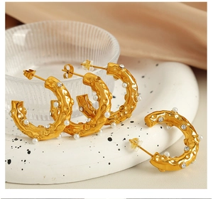 Detail of C-shaped 18K gold earrings with hammer texture, pearls and crystals