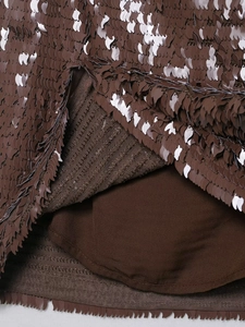 Détail macro de broderies de paillettes marron foncé sur tissu en maille pour mini-jupe
