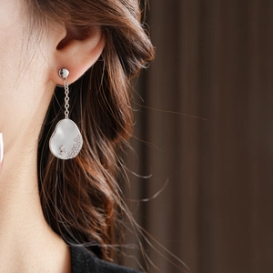 Gros plan d'une boucle d'oreille asymétrique plaquée or 18k avec pendentif en cristal