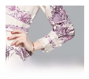 Detail of ruffled cuffs with purple floral print and a pearl button on the dress sleeve