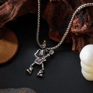 Détail du pendentif tête de mort à la guitare en argent avec chapeau doré sur fond sombre