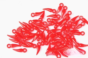 Close-up of small red plastic chili charms with hanging rings for DIY crafts