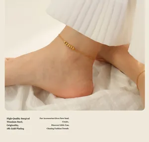 Detail of 18k gold plated titanium steel anklet with five beads on model's ankle