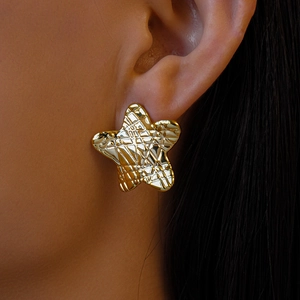Gros plan d'une boucle d'oreille étoile dorée texturée portée par un mannequin
