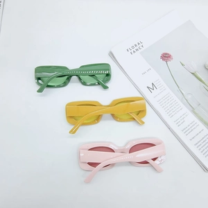 Flat lay of retro square sunglasses in green, yellow, and pink on white background