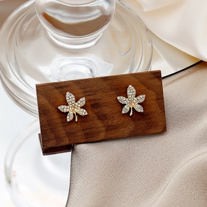 Macro shot of maple leaf earrings with inlaid crystals on a golden metal base