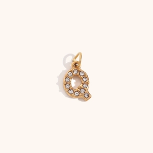 Detalle del colgante letra Q bañado en oro 18K con brillantes cristales pavimentados