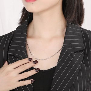 Detail of silver beaded chain necklace worn over a black and white striped suit