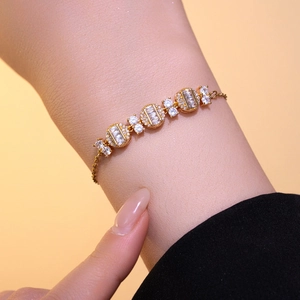 Elegant gold bracelet with geometric zircon crystals worn on wrist with adjustable chain