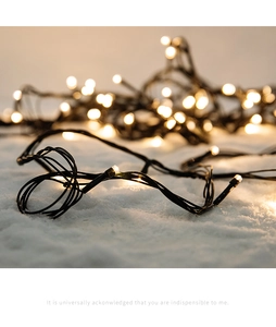 Macro shot of warm white LED Christmas lights on snow-textured background with black cable