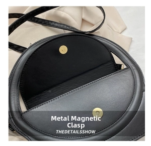 Detail der hochwertigen Magnet-Metallschnalle an einer schwarzen Umhängetasche aus Leder