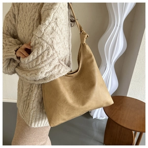 Detail of knotted shoulder strap and vintage faux leather texture on the light brown bag