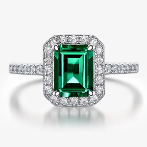Macro shot of silver ring with emerald cut green gemstone and small faux diamonds