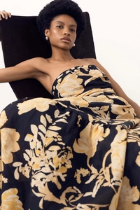 Close-up of strapless maxi dress featuring retro yellow floral prints on black fabric