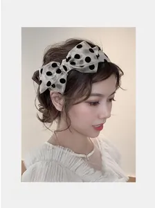 Close-up of a sweet beige polka dot bow headband with elegant sheer texture on a model