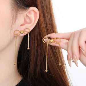 Détail de boucles d'oreilles papillon en acier doré avec de longues franges élégantes