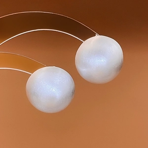Macro detail of round white pearl earrings with metallic plating and polished finish