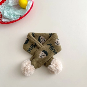 Detail of knitted kids scarf with embroidered face motif, 'Mine' text and beige pom-poms