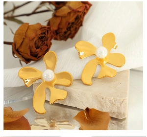 Détail de boucles d'oreilles fleur dorées vintage avec perles sur pierre et tissu blanc