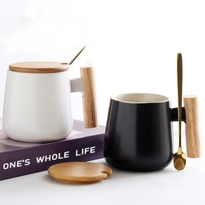 Nordic ceramic mugs in black and white with wooden handles, lids, and gold spoons