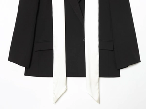 Détail d'un blazer noir avec rubans de soie blancs contrastés et texture de tissu fine