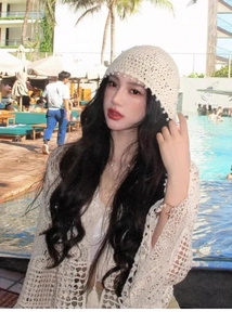 Dettaglio cappello in maglia beige con perle e cardigan coordinato a bordo piscina