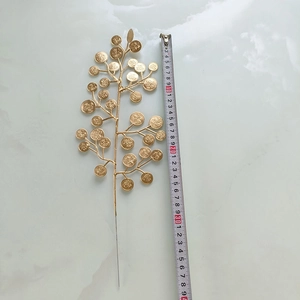 Vue détaillée d'une branche de feuilles dorées avec pièces de fortune et ruban à mesurer
