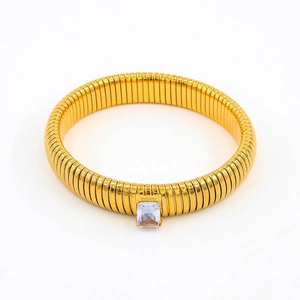 Detailed macro of gold snake-coil flexible bracelet featuring a rectangular zircon stone