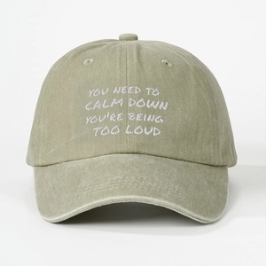 Detail of white slogan embroidery on a vintage washed green cotton baseball cap