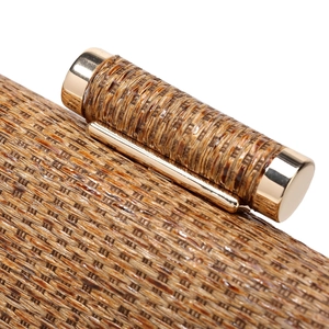 Detail of a brown woven evening bag with a gold metal clasp and textured straw finish