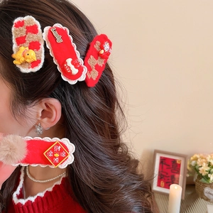 Détail de pinces à cheveux festives en velours rouge avec dragon doré et texte Lucky