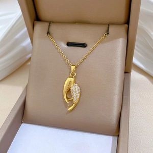 Gros plan du pendentif doré courbé avec zircons sertis sur une boîte en cuir