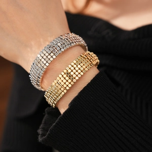 Gros plan de bracelets larges multicouches en métal doré et argenté sur une manche noire