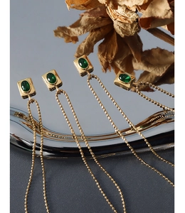 Macro shot of four gold beaded necklaces featuring oval green gemstones in square settings