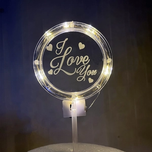 Macro shot of glowing acrylic heart cake topper with warm LED lights and I Love You text
