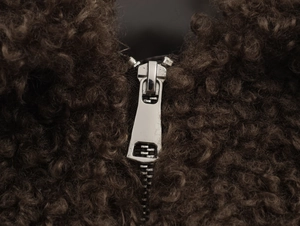 Macro shot of silver metal zipper and brown faux shearling texture on jacket