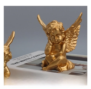 Close-up of golden resin angel statue in sitting pose with detailed wing textures