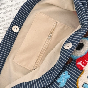 Detailed view of striped canvas bag interior with metal zipper and magnetic closure