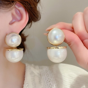 Vue détaillée des boucles d'oreilles à double perle blanche avec lien doré poli