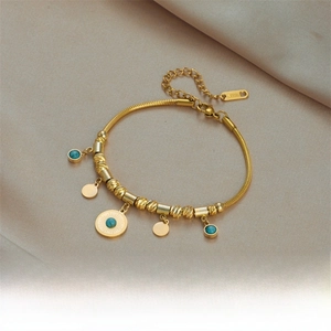 Detail of gold-plated stainless steel snake chain with turquoise beads and metal charms