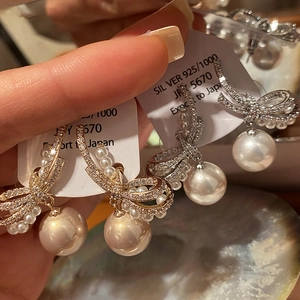 Macro view of S925 silver bowknot earrings with lustrous white pearls and zircon stones