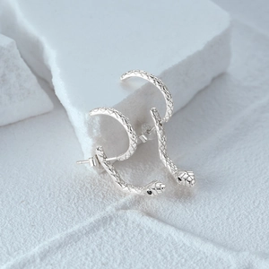 Macro shot of S925 sterling silver snake earrings with textured scales on stone
