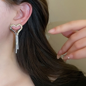 Close-up of long silver heart tassel earrings with sparkling rhinestones on model