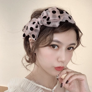 Elegant pink organza headband with black polka dots and a large bow on model