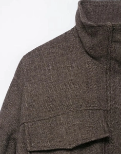 Detail of dark brown herringbone bomber jacket showing collar, stitching and patch pockets