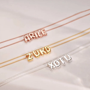 Detailed view of 3D bubble letter necklaces in rose gold, gold, and silver finishes