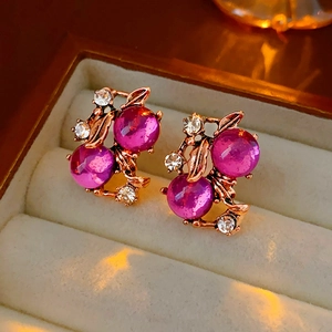 Close-up of vintage gold earrings with pink gemstones and rhinestones in a jewelry box
