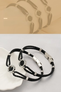 Macro detail of braided black leather bracelet with stainless steel compass charm and clasp