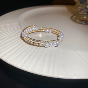 Close-up of double-layer gold plated bangle with pearls and sparkling zircon accents